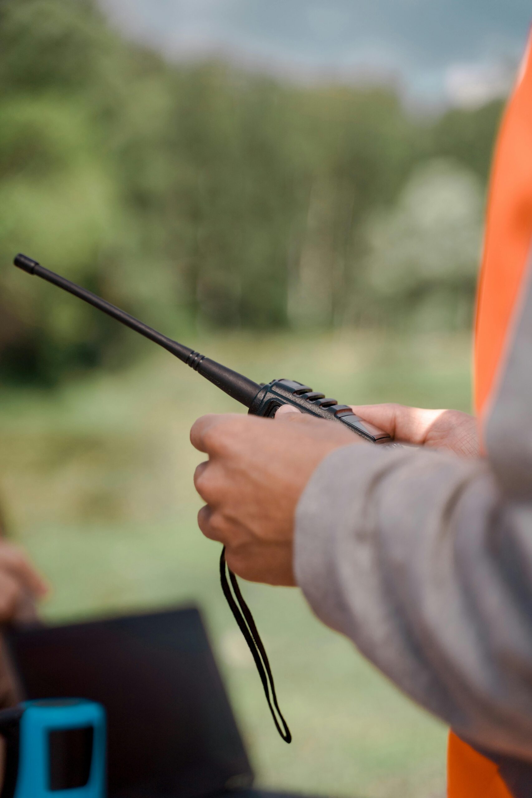 A person holding a walkie talkie during an outdoor search effort.