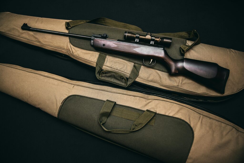 Close-up of a hunting rifle with a scope on a carrying bag, showcasing firearms and hunting gear.